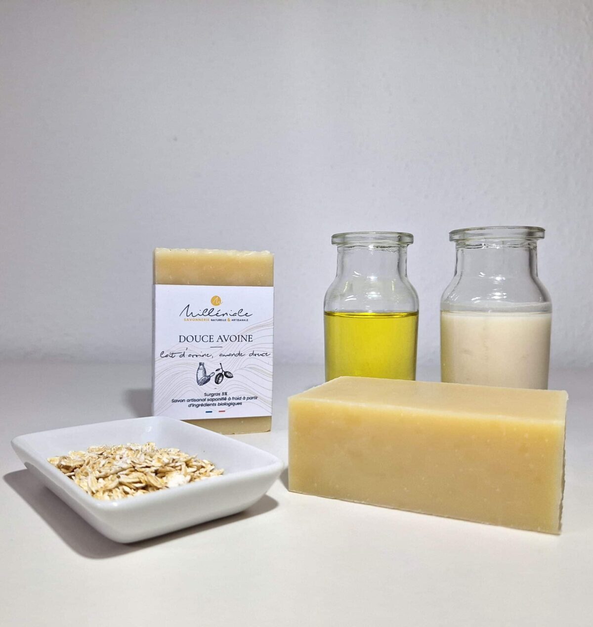Savon Douce Avoine Milléniale avec et sans étiquette, accompagné de flocons d’avoine, huile d’amande douce et lait d’avoine.