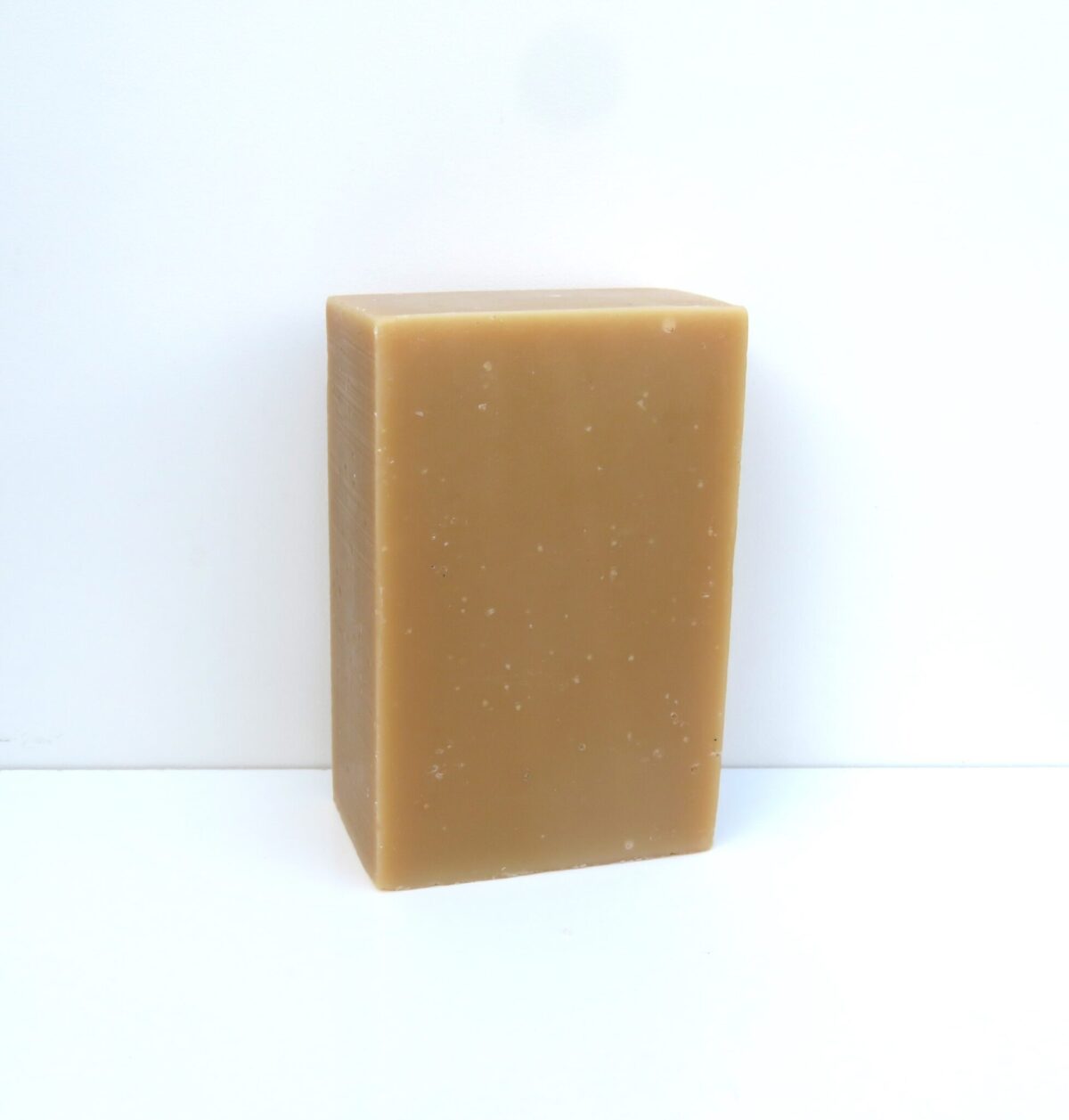 Savon naturel peau sensible au miel et cire d’abeille, pain artisanal nu sur fond blanc.